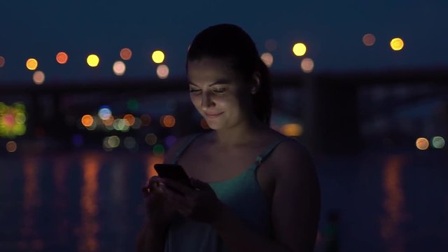 the girl uses a smartphone while walking on a night beach. HD