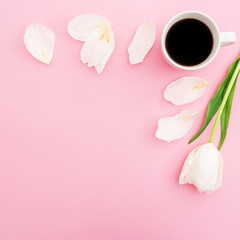 Pastel composition with white tulip flowers, petals and mug of coffee on pink background. Frame background. Flat lay, top view.