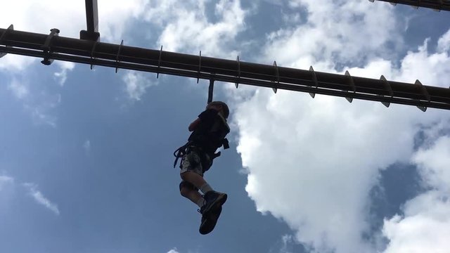 My son riding a zip line for the first time, having fun.
