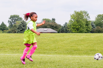 A young girl is learning how to play soccer