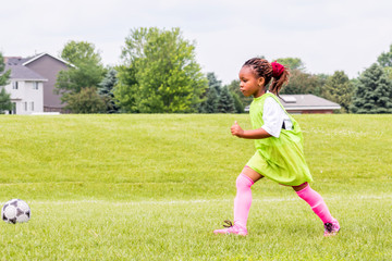 A young girl is learning how to play soccer