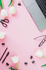 Desk with laptop, white flowers, cosmetics, glasses and pen on pink background. Flat lay. Top view. Business concept with copy space
