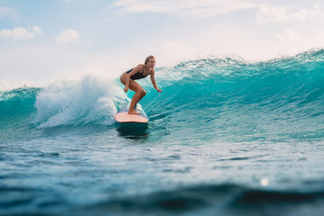 Beautiful surfer girl on surfboard. Woman in ocean during surfing. Surfer and wave - obrazy, fototapety, plakaty