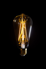 Illuminated Edison Light Bulb Floating In Air Against A Black Background. Thought Or Idea Concept...