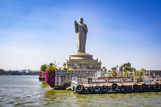 Sailing By The Giant Buddha Statue With Bright Pink Bougainvillea Plants In The Middle Of Hussain Sagar Lake In Hyderabad, India