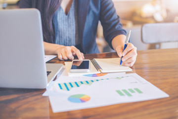 Business woman are writing analysis logs about charts and graphs that show results in the office.
