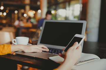 Young business female hands using smart phone while working on computer.