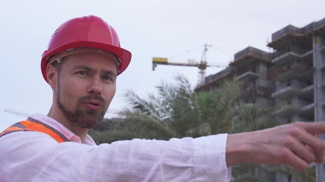 Man in a helmet, architect, engineer, manager tells about the progress of construction in evening stock footage video