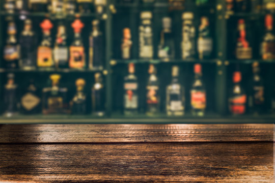 Empty the top of wooden table with blurred counter bar and bottles Background /fFor montage product display