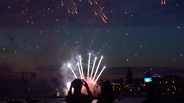A group of people watching fireworks at night by the river. slow motion. HD