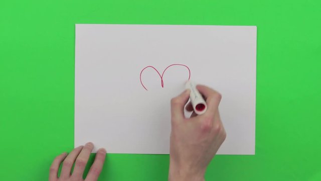 drawing a red heart on a papper on a green screen. meaning of love for valentine days