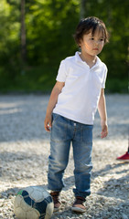 Cute caucasian toddler boy playing with soccer ball in the park at sunny day