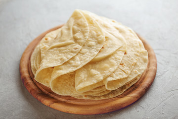Homemade wheat flour tortilla on wooden cutting board.