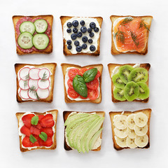 Set of various toasts with fruit, vegetable, fish and sausage and cheese on white baking paper. - 210781672