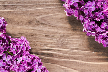 lilac flowers in the left down and right up corners on the brown wooden surface. Sharp focused nice photo
