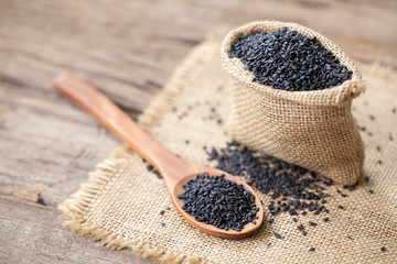 black sesame seeds on sack cloth and wooden background