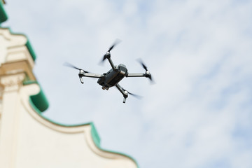 drone quadcopter with digital camera hovering over city