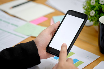 Cropped shot of an unrecognizable woman using mobile phone at desk.