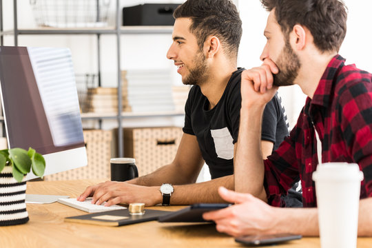 Excited stockbrokers buying virtual money while using computer