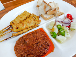 Pork Satay Thai Food, Grilled Pork with Bread in White Plate on Wooden Table, Satay, or sate in Indonesian spelling, is a dish of seasoned