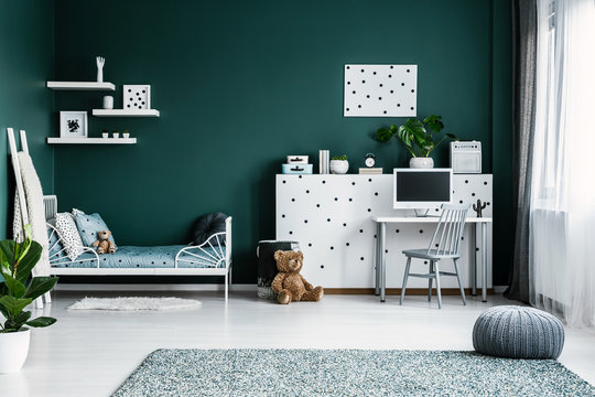 Cozy bedroom interior with teddy bears, single bed, desk and computer, dotted wall and pouf on the carpet. Place your product