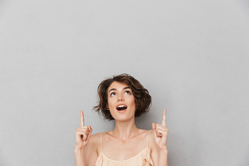 Portrait of a surprised young woman pointing fingers up