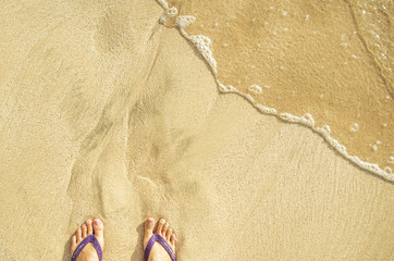 Fototapeta na wymiar Refreshing sea and sandy beach. First person sight. Feet at sea comb.