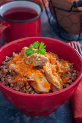 Buckwheat porridge with meat in a red bowl, selective focus