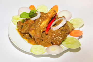 Popular Indian meal of spicy mutton gravy popularly known as mutton kosha with chili and sliced vegetables.
