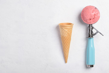 Ice cream spoon with homemade icecram scoop with wafer cone on white table background topview...