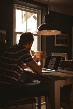 Man having coffee while using a laptop
