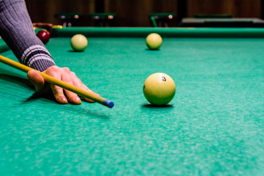Player arm with the cue and balls on the green cloth. Russian billiard