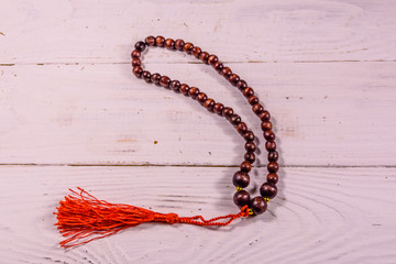 Brown rosary on the white wooden table. Top view