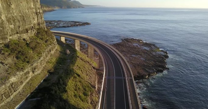 Driving along the Sea Cliff Bridge, south of Sydney in New South Wales, Australia. Coastal drive along a highway suspended over the coast line with mountains on one side and the ocean on the other.