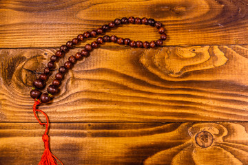 Brown rosary on the wooden table. Top view
