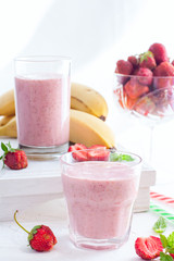 Smoothies of strawberries and bananas in glass glasses on a white table, selective focus