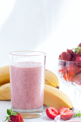 Smoothies of strawberries and bananas in glass glasses on a white table, selective focus
