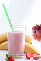 Smoothies of strawberries and bananas in glass glasses on a white table, selective focus