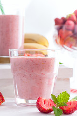 Smoothies of strawberries and bananas in glass glasses on a white table, selective focus