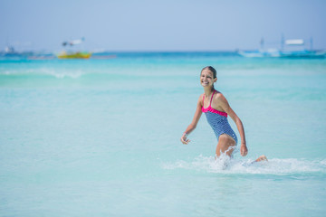 Girl in swimsuit runing and having fun on tropical beach