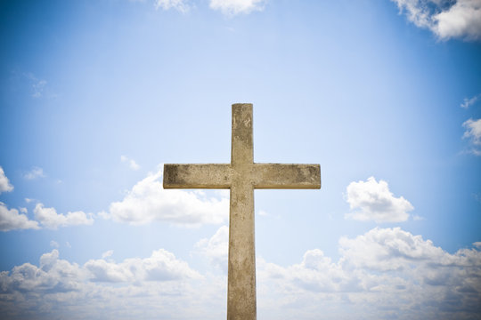 Concrete christian cross against a bright sky - concept image with copy space