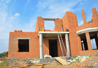 Fototapeta premium Brick house building construction. Brick building unfinished house construction with entrance door, balcony and columns.