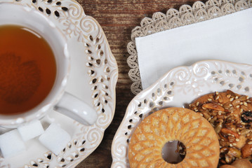 various cookies and biscuits baked at home in a container and tea in a retro cup with free space for text