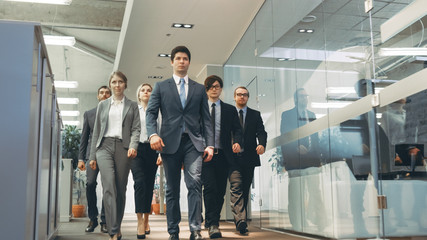Diverse Team of Delegates/ Lawyers Confidently Marching Through the Corporate Building Hallway. Multicultural Crowd Of Resolute Business People in Stylish Marble and Glass Offices. - obrazy, fototapety, plakaty