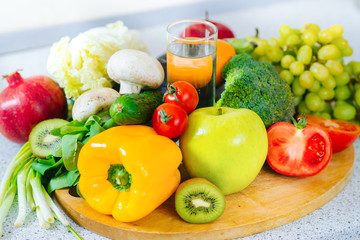 Many different fruits and vegetables with glass of water in the middle of