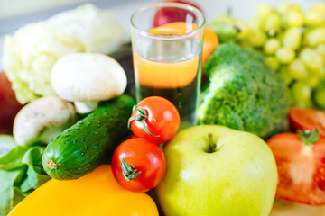 Many different fruits and vegetables with glass of water in the middle of