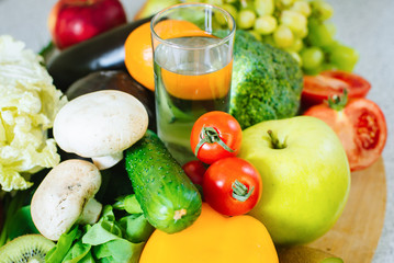 Many different fruits and vegetables with glass of water in the middle of