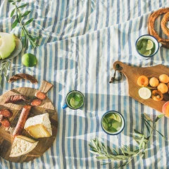 Fotobehang Picknick Platte zomerpicknickset met fruit, kaas, worst, bagels en limonade over gestreepte deken, bovenaanzicht, kopieerruimte, vierkant gewas