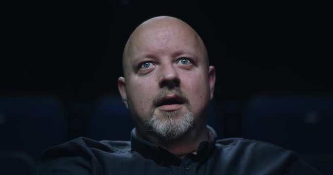A surprised reaction from a man at the movie theatre. Slow motion.