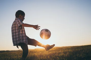 Poster Young little boy playing in the field  with soccer ball. © altanaka